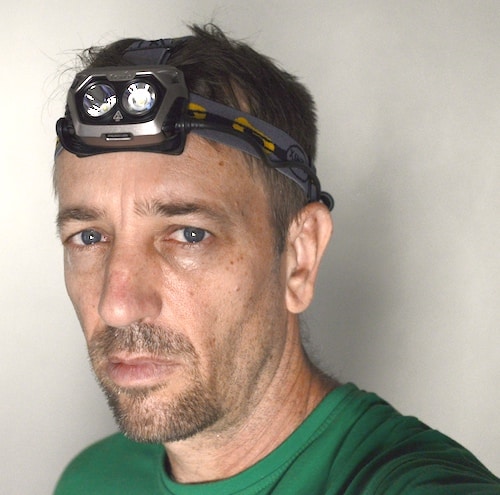 Model wearing Fenix HP25 headlamp with grey strap on head.